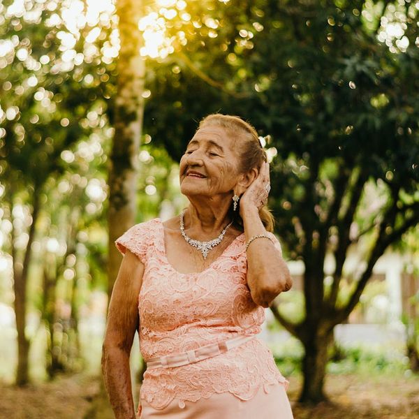 A person smiling peacefully with eyes closed outdoors.